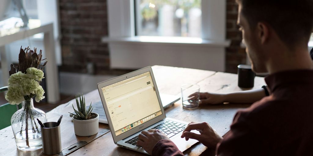 man operating laptop on top of table